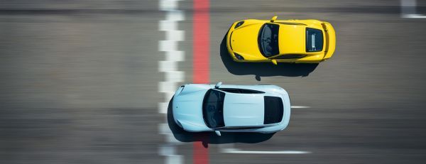 Zwei Porsche Sportwagen fahren nebeneinander auf einer Rennstrecke.